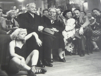 black and white photo of people sitting in chairs watching something