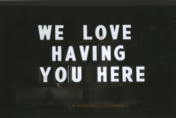Black background with white words that say "We Love Having You Here"