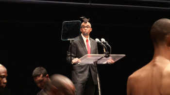 male speaker behind podium, male back of head shoulders