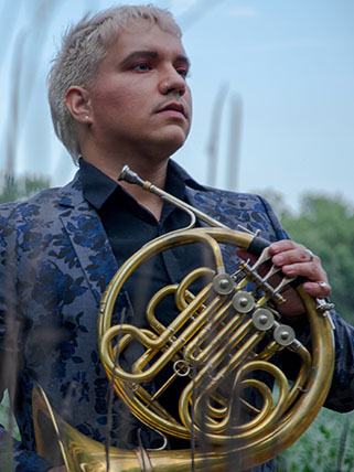 Smiling person holding a french horn