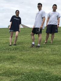Three students standing in a grassy area