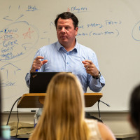 male teacher lecturing in front of whiteboard