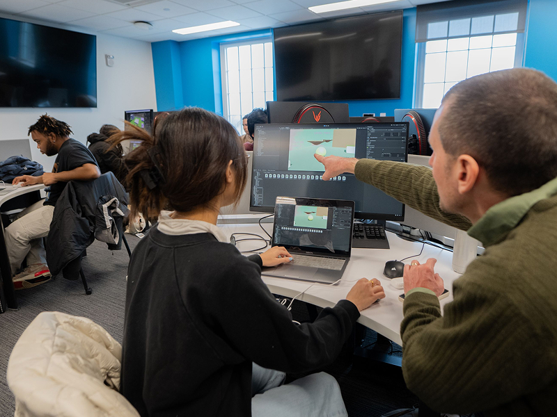 student with teacher pointing to computer screen