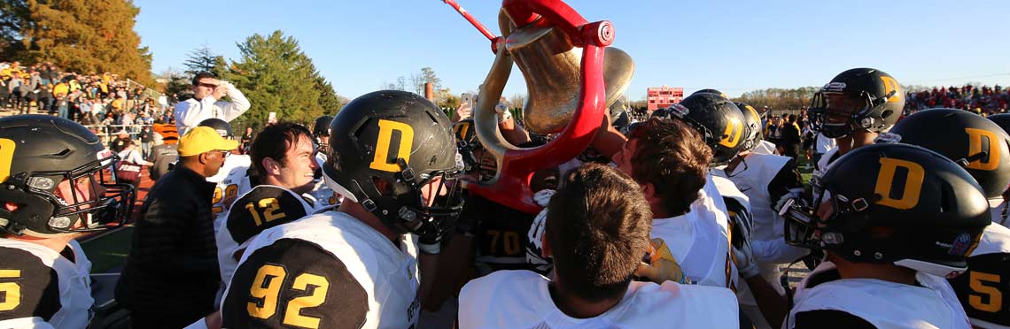 Football players hoist the Monon Bell following a win