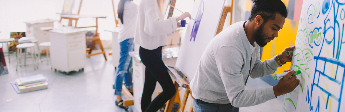 Students painting on canvas in an art class