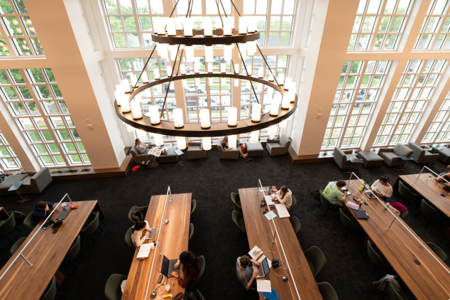 overhead shot of library building with large windows and students sitting at tables