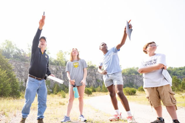 An instructor and students exploring an outdoor rock quarry