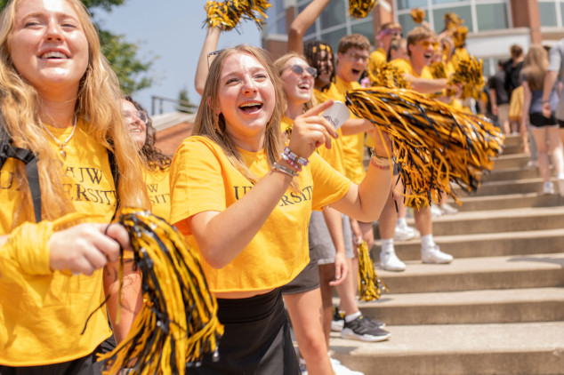 students cheering on new students walking up steps