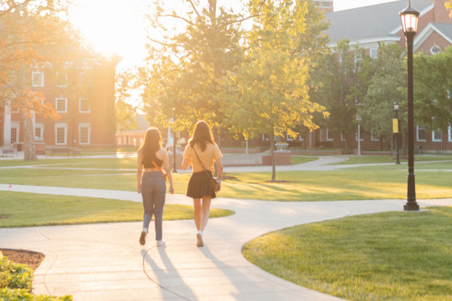 two females walking on sidewalk at sunset