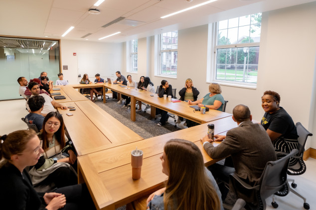 Students, staff, and faculty conversing around a table