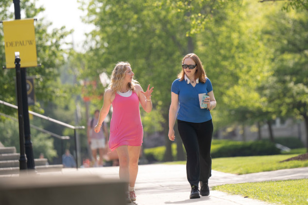two females walking on sidewalk on campus