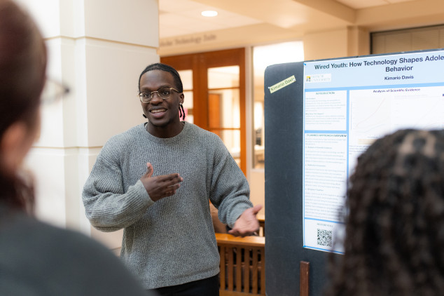 Student presenting Honor Scholars poster in front of a group
