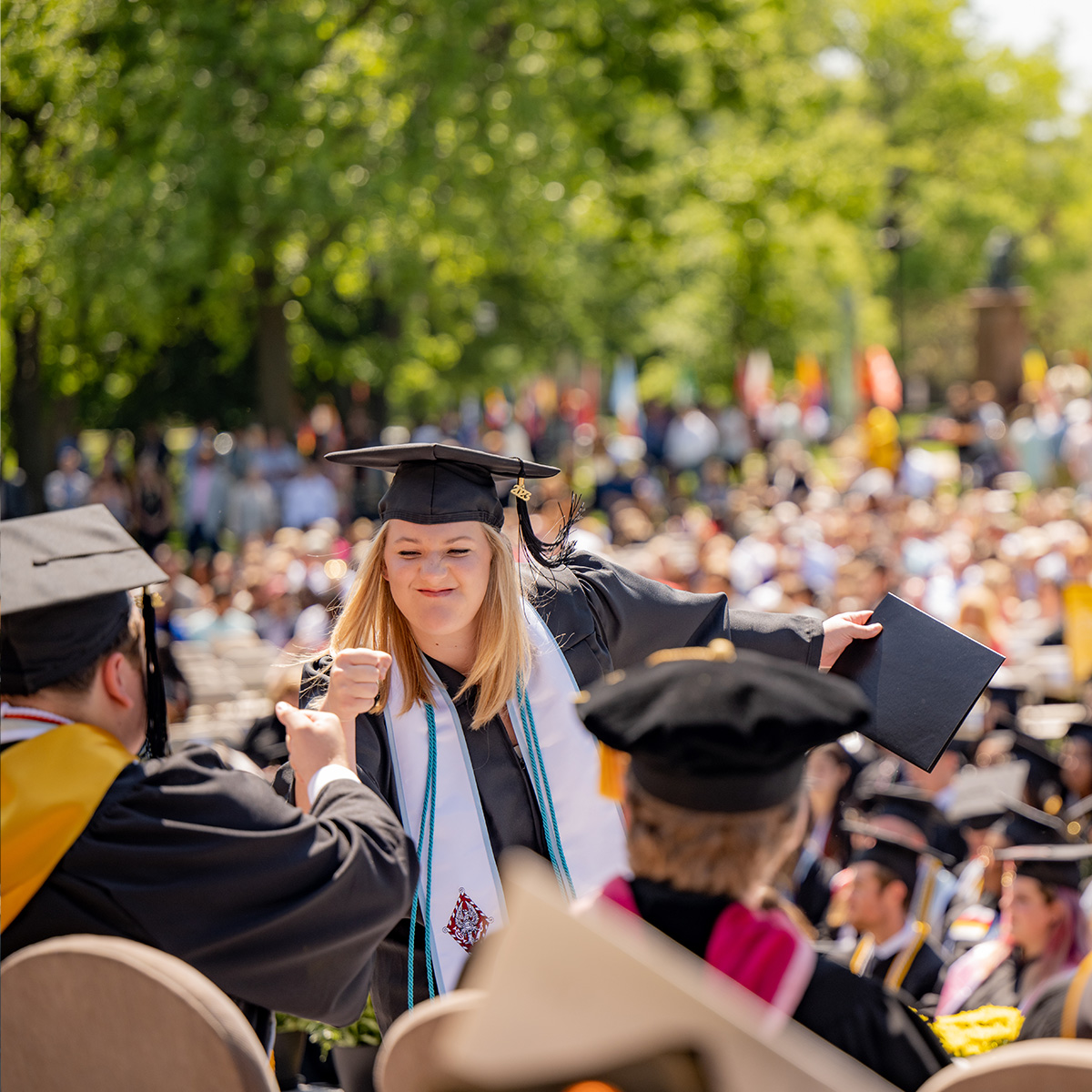 Student fist bumping professor during commencement ceremony