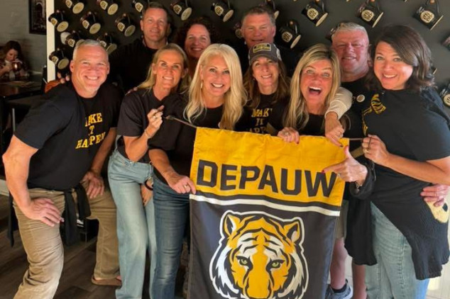 large group of people holding a depauw flag
