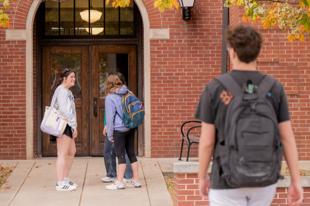 students with backpacks standing in front of brick building