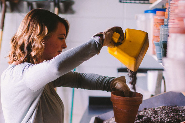 Student pouring dirt into a flower pot
