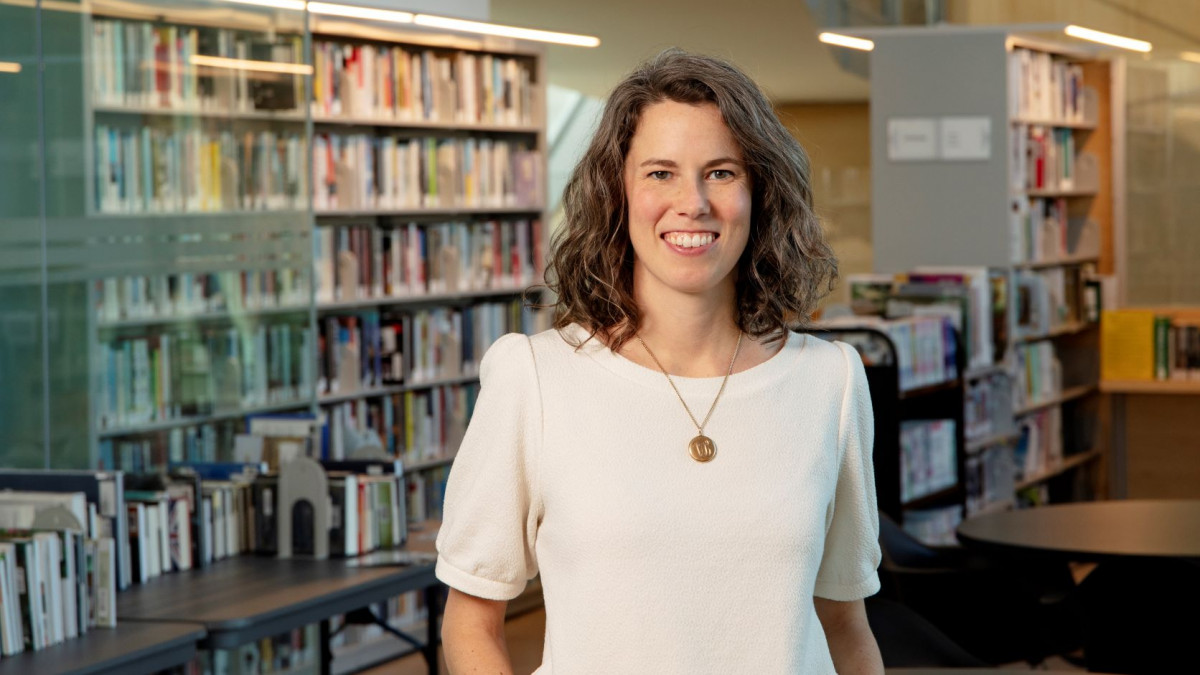 Elizabeth Blue Guess '10 stands in front of bookshelves