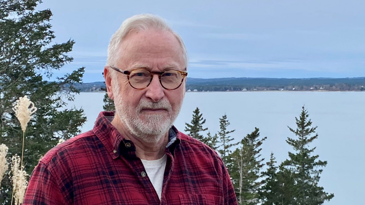 Doug Frantz '71 in front of a lake and trees on his Canada property 