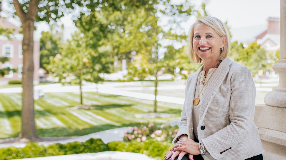 Jennifer Pope Baker '89 sits on a railing on campus