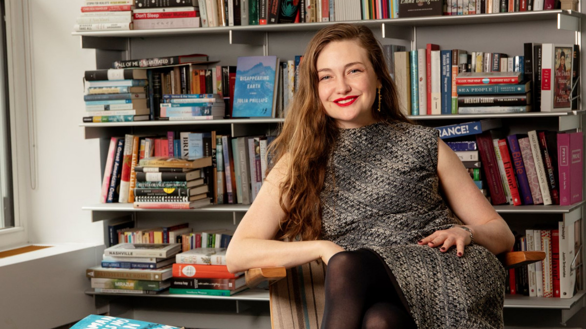 Erin Wicks '11 sits in front of a full bookshelf