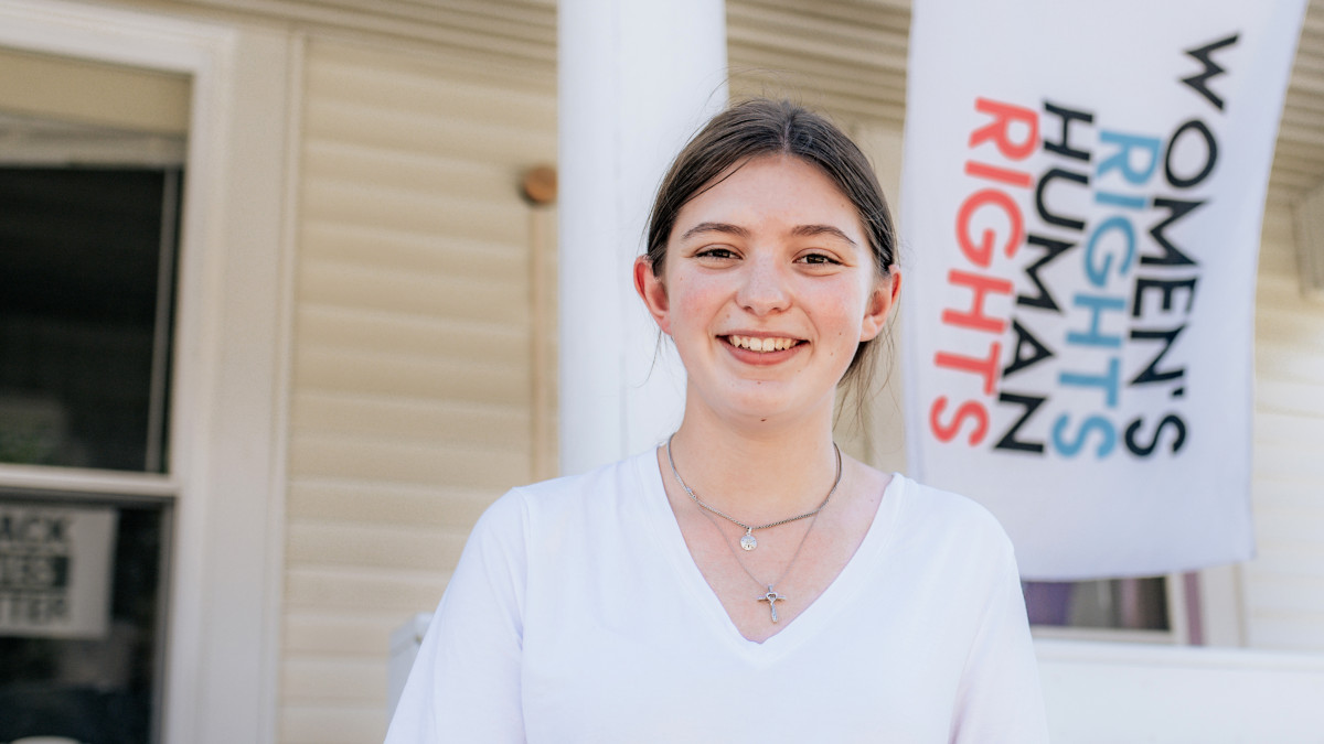 Zoe Knight '25 in front of a Women's Rights are Human Rights flag