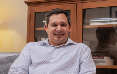 Trevor Yuhas, director of counseling services, sits in front of a bookcase.