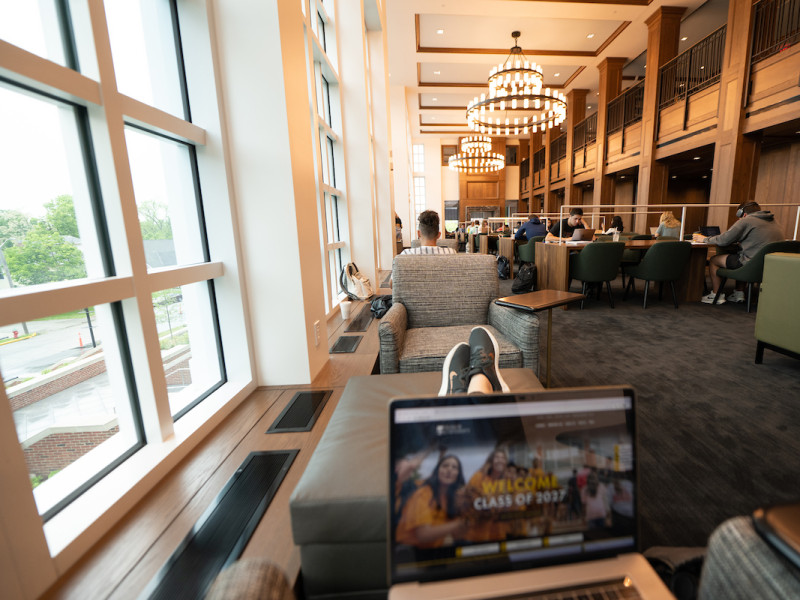Student studying with laptop in library reading room