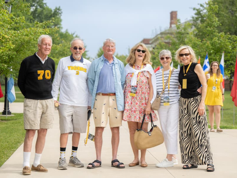 Six alumni posing together on a campus walkway during a reunion