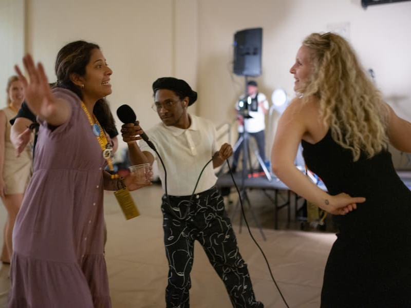 Students dancing and singing into a microphone at an indoor party