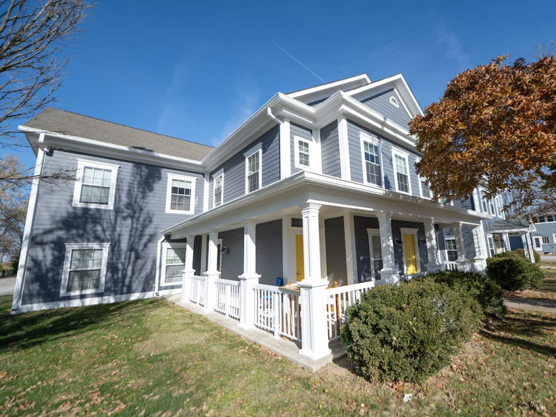 Modern blue and gray duplex with yellow door and porch