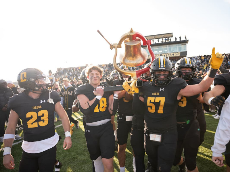 Football players celebrating victory while carrying the bell