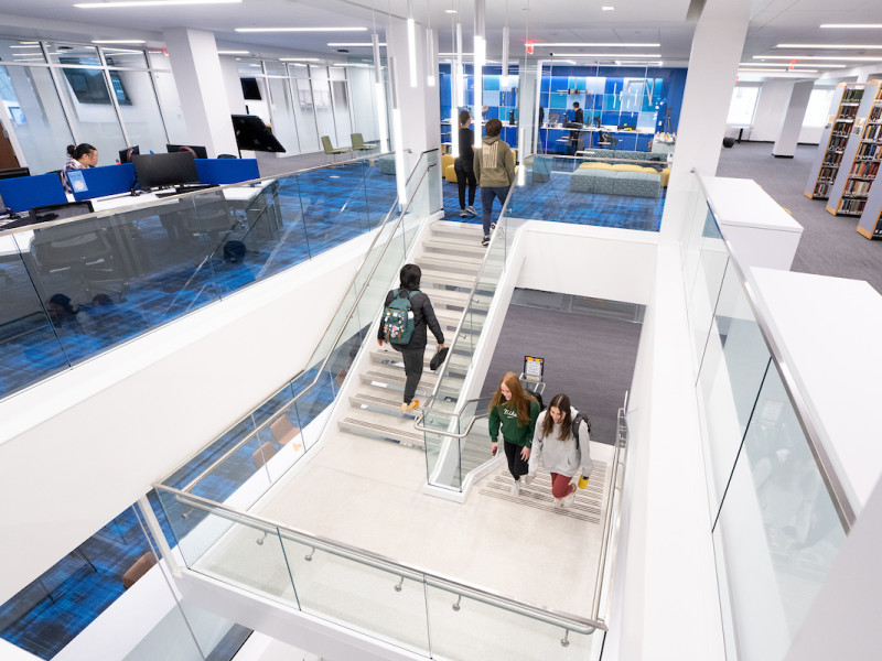 Modern library staircase with glass rails and blue carpet