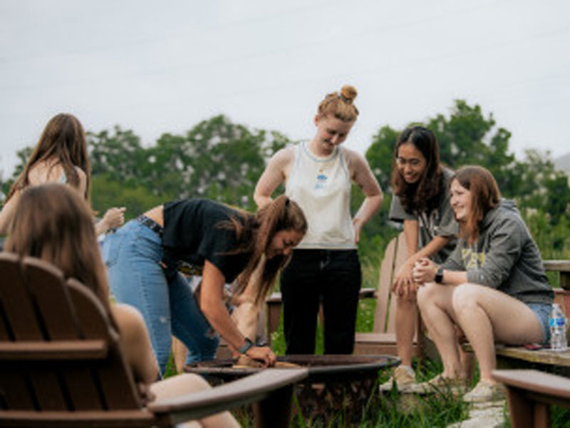 Students gathered around an outdoor fire pit