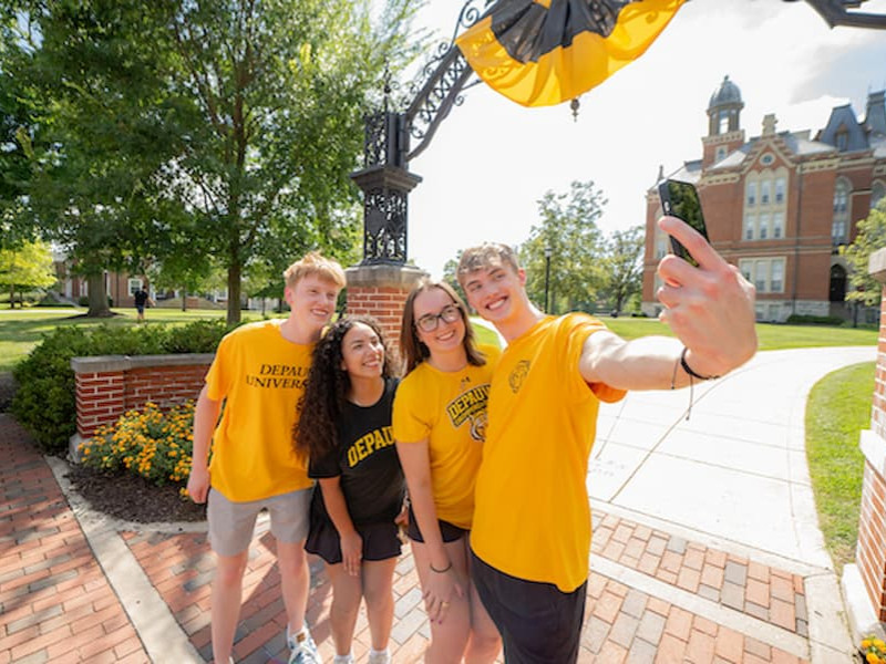 DePauw University students smiling and taking a selfie together on campus.