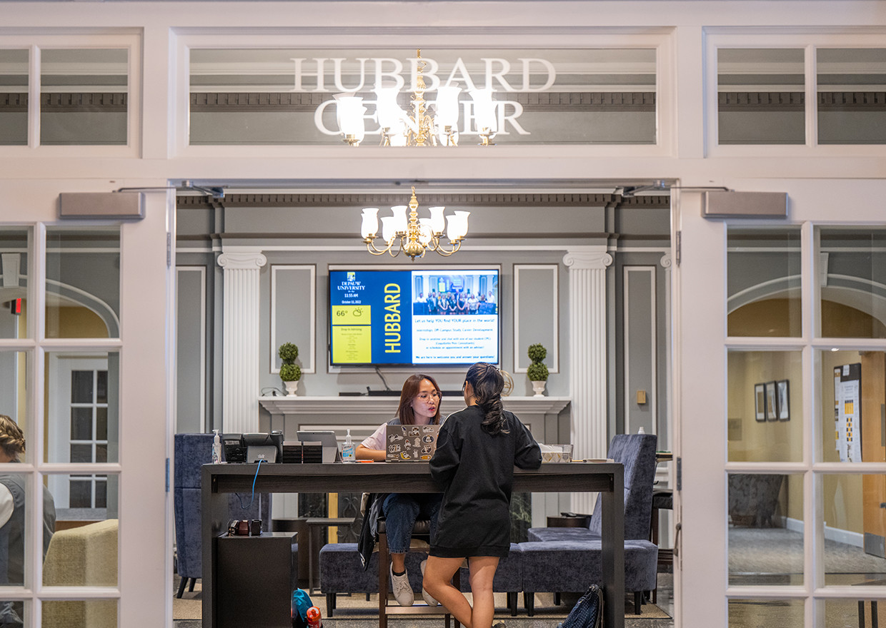 View through the Hubbard Center entrance to two students working across from each other at a table.