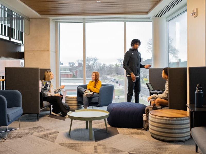 Students talking in a modern campus lounge with large windows