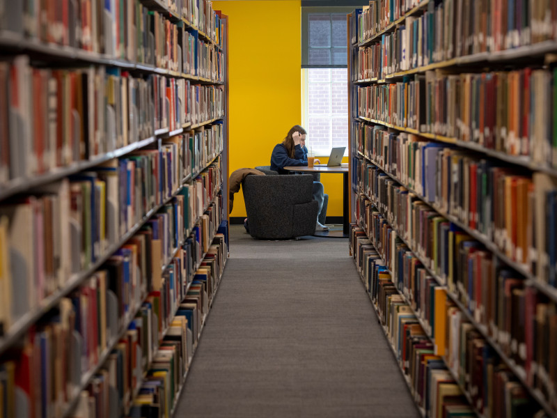 View down a library aisle of a student working