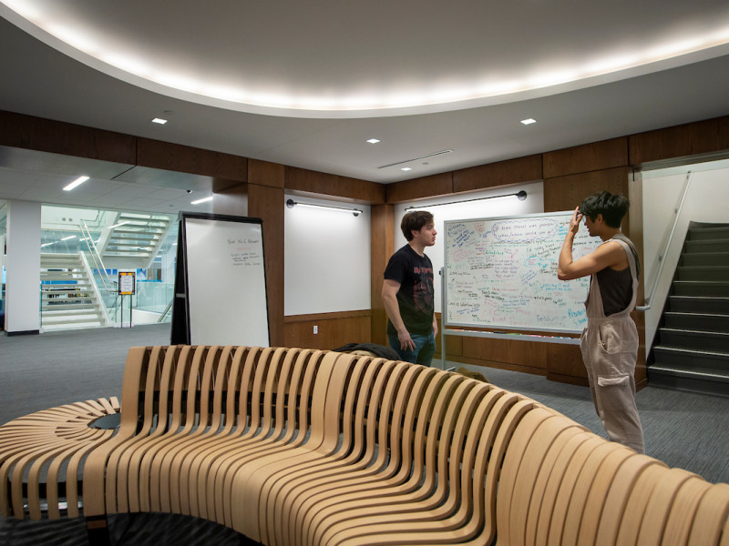 A curved wooden bench in a campus library lounge