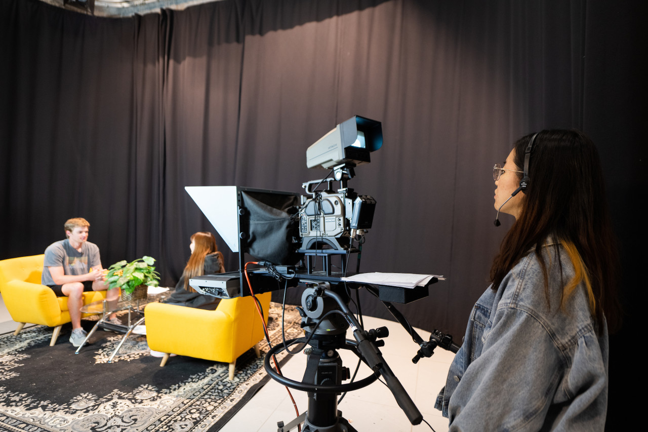Student filming two students in gold chairs at D3TV Television Studios