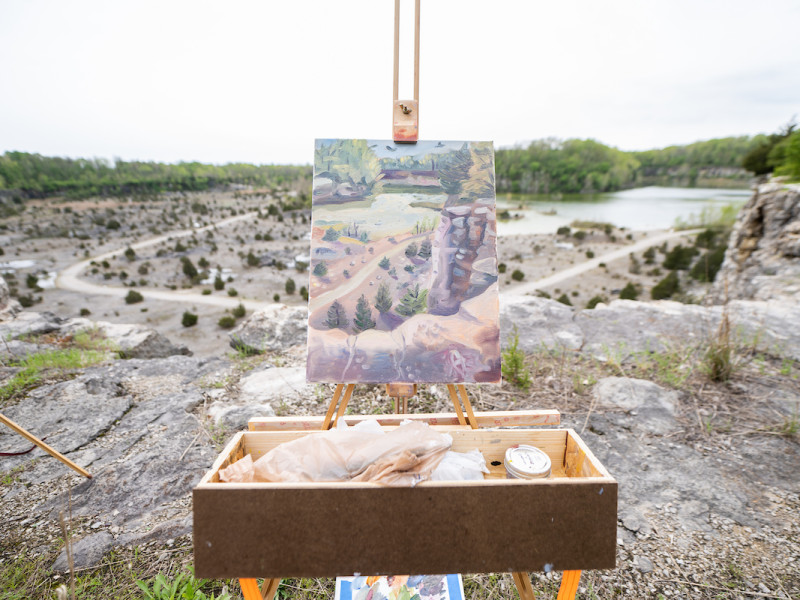 Landscape painting on an easel overlooking a rocky quarry