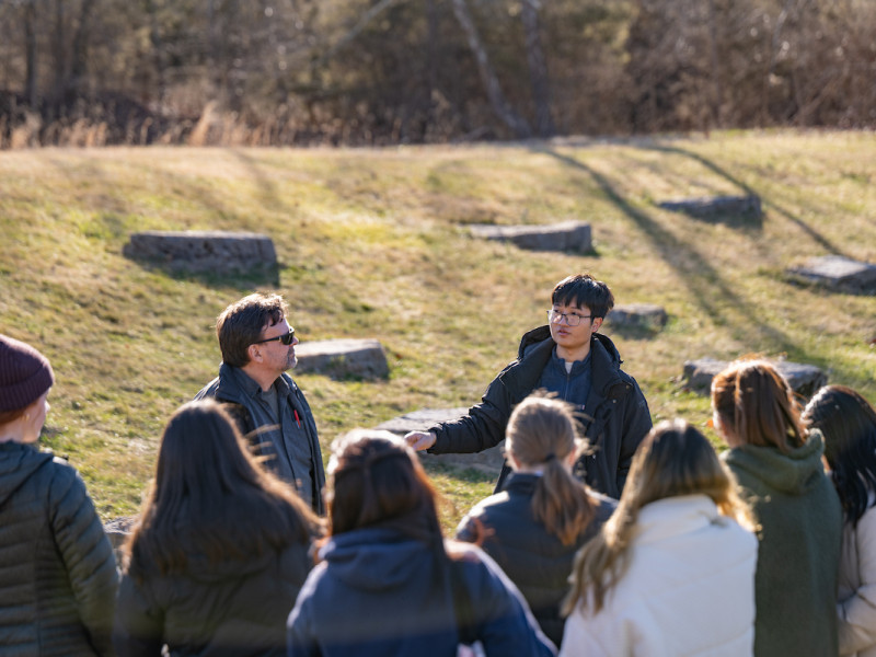 Students and instructor standing in a grassy field area