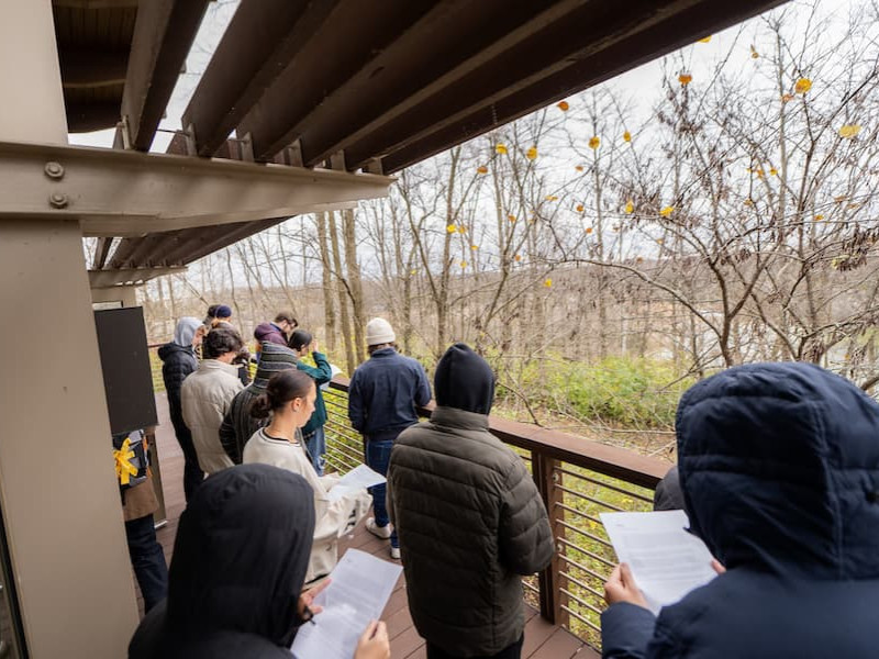 Students gathered on an outdoor balcony holding papers