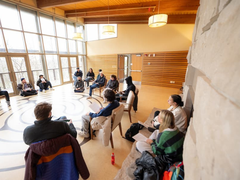 Students in a circle discussion in a sunlit room
