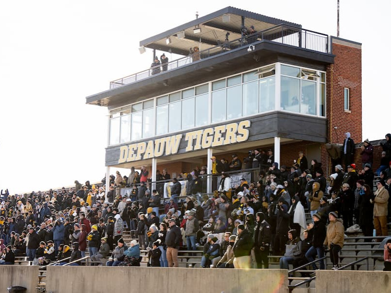 Crowded stadium bleachers under a DePauw Tigers press box