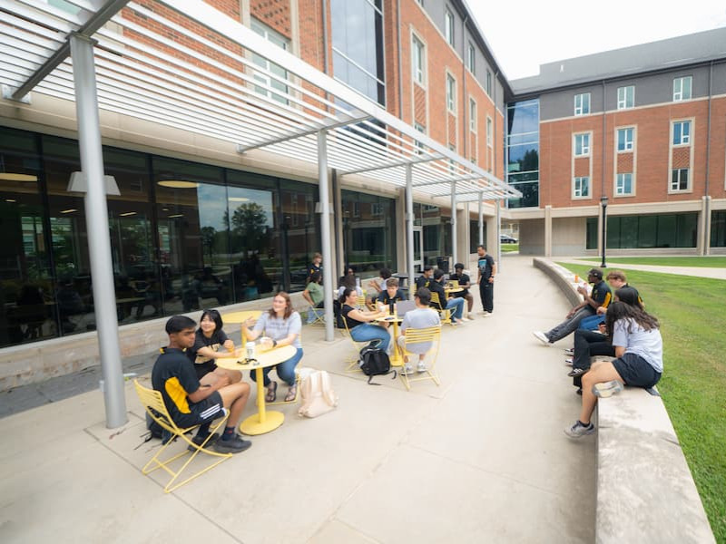 Students studying and socializing at outdoor tables on campus