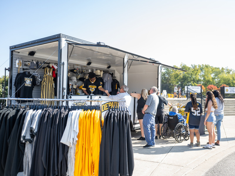 Fans browsing apparel at a mobile university merchandise trailer