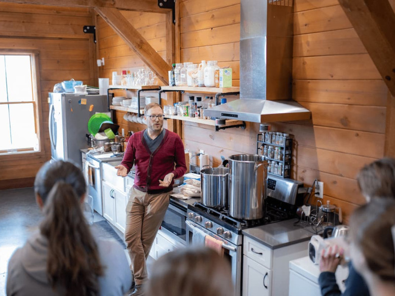 An instructor speaking to a group in a rustic kitchen