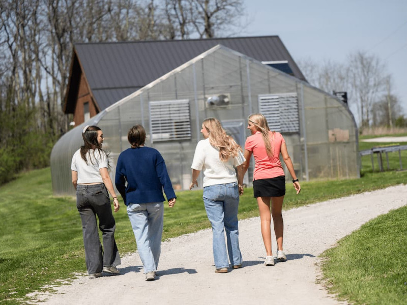 Four individuals working in the soil at a campus farm