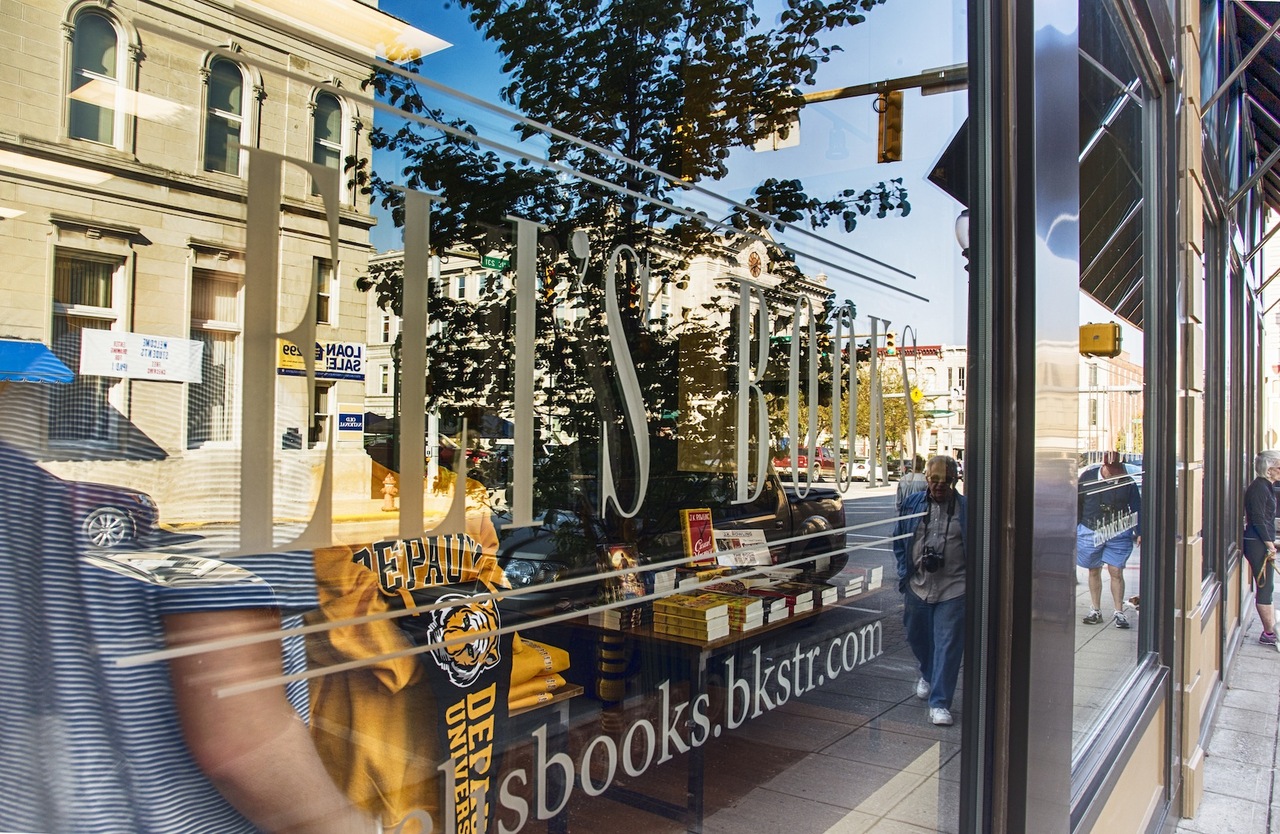 Window of Eli's Books showing reflection of downtown Greencastle buildings.