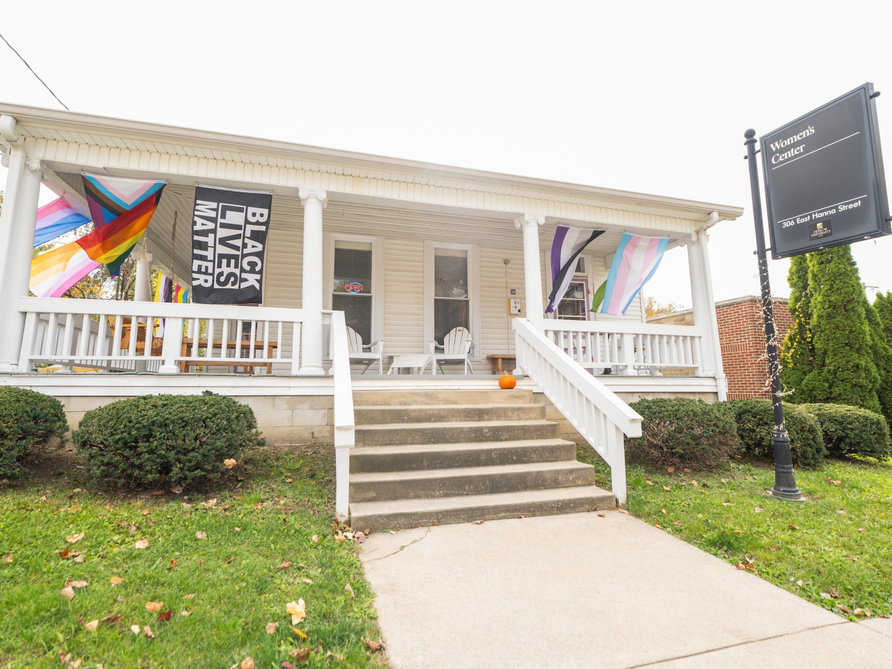 Exterior of the Women's Center, a white and brick building with BLM and LGBTQIA flags hanging on the patio.